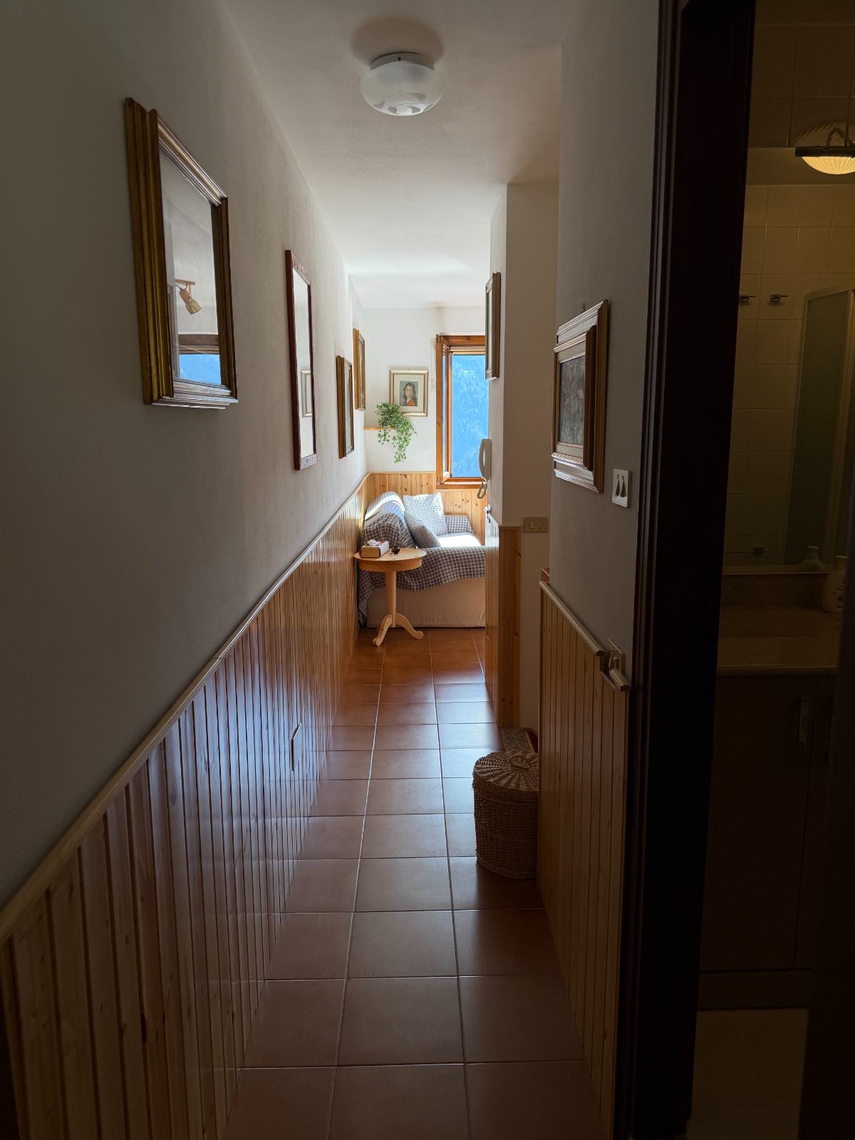 Corridoio con boiserie in pino e quadri incorniciati